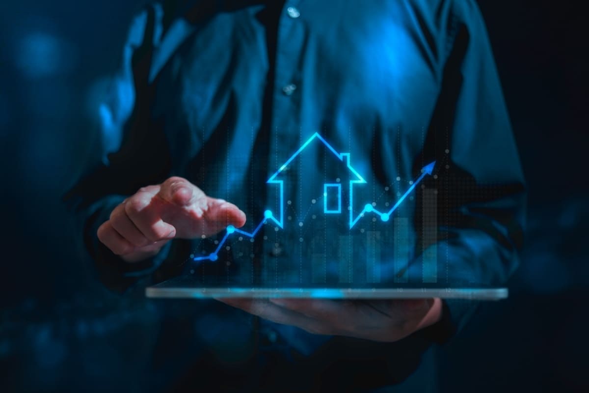 Man with tablet in his hands projecting a graph going up with a house drawn in the middle