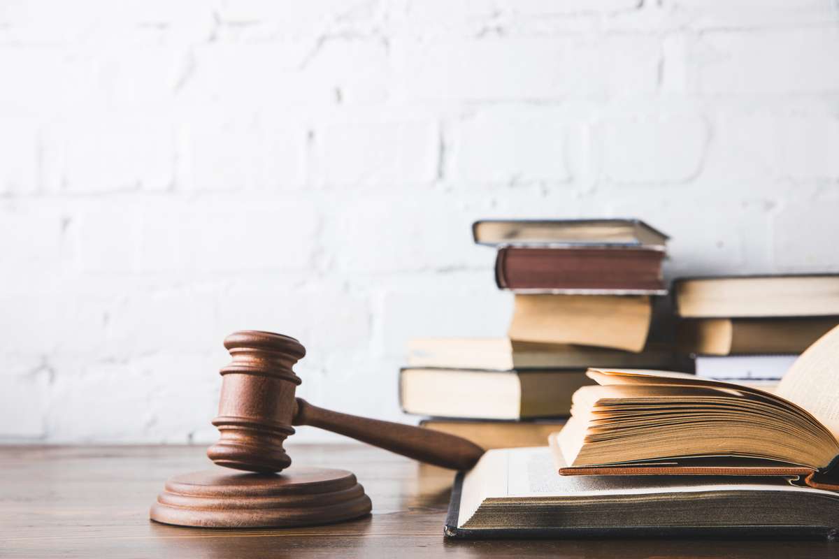 Opened juridical books with gavel on wooden table, law concept