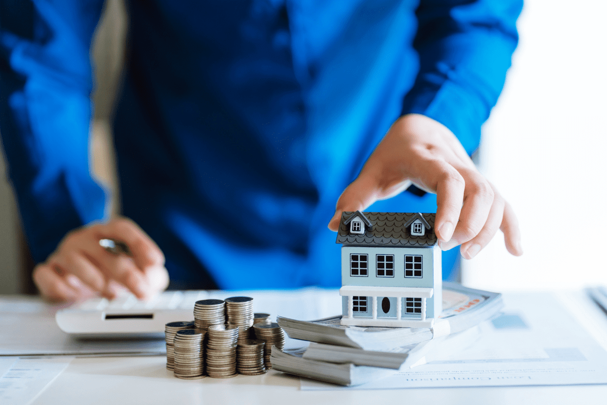 roperty manager calculating returns on calculator with model house in one hand